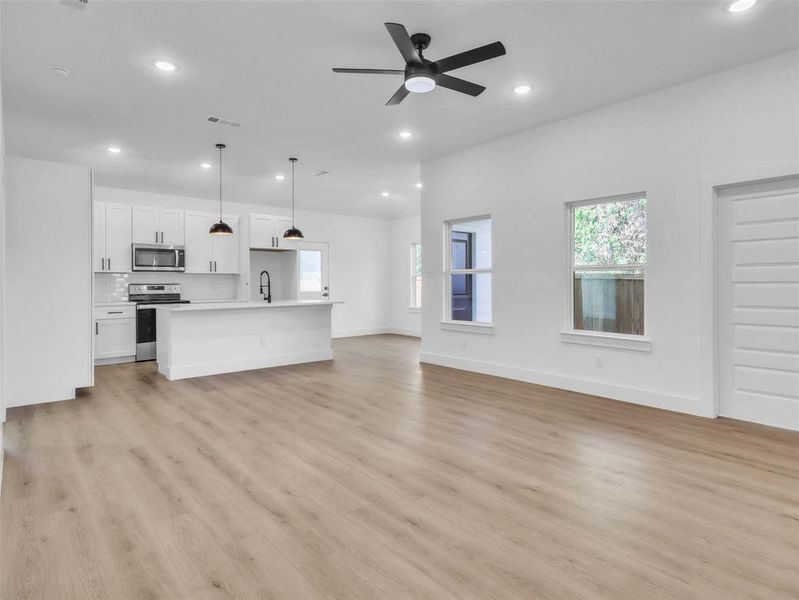Unfurnished living room with light wood-style floors, a sink, visible vents, and recessed lighting Unfurnished living room with light wood-style floors, a sink, visible vents, and recessed lighting