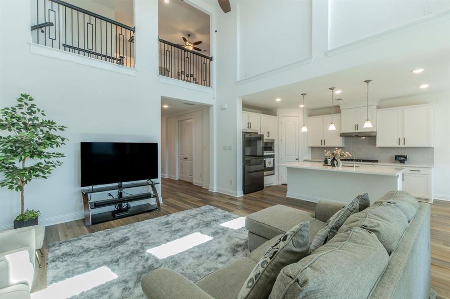 Open-concept living space featuring high ceilings, wood-finish flooring, and a modern kitchen with a center island