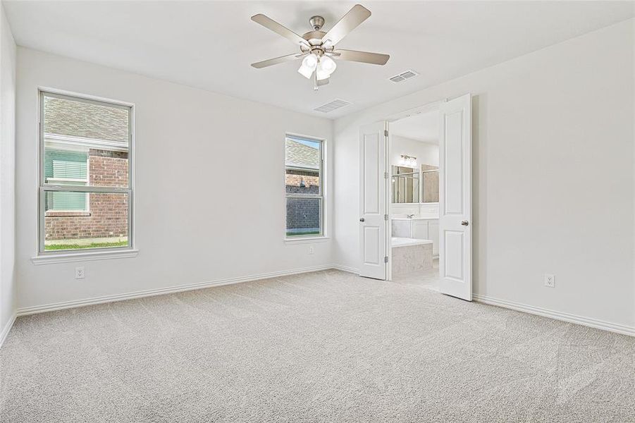 Unfurnished bedroom with light colored carpet, ceiling fan, and ensuite bathroom