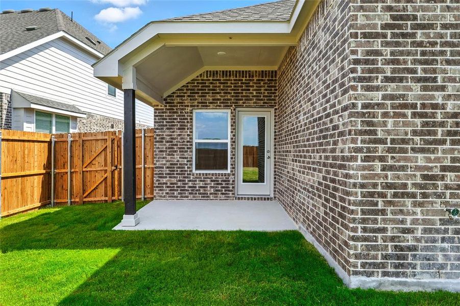 Doorway to property with brick siding, a gate, and a patio area Doorway to property with brick siding, a gate, and a patio area