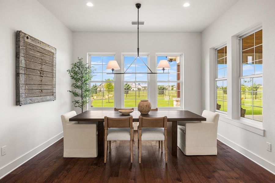 Virtually staged dining space with natural light streaming in from wall of windows and view to back yard, dark engineered wood-type flooring, recessed lighting, and a chandelier Virtually staged dining space with natural light streaming in from wall of windows and view to back yard, dark engineered wood-type flooring, recessed lighting, and a chandelier