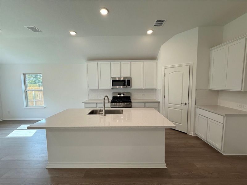 Kitchen with white cabinets, appliances with stainless steel finishes, recessed lighting, dark wood-type flooring, and a center island with sink Kitchen with white cabinets, appliances with stainless steel finishes, recessed lighting, dark wood-type flooring, and a center island with sink