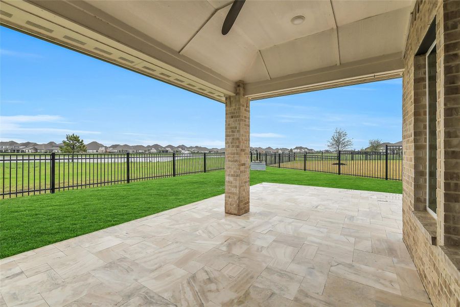 Generous covered patio space overlooking the backyard and scenic surroundings, perfect for outdoor dining or relaxing while enjoying the view.