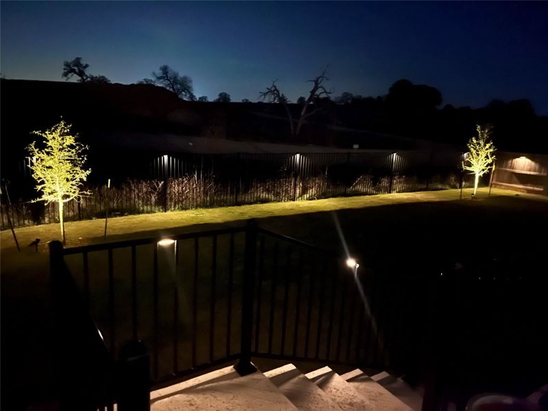 Illuminated backyard landscaping creates an inviting ambiance under the twilight sky. Illuminated backyard landscaping creates an inviting ambiance under the twilight sky.