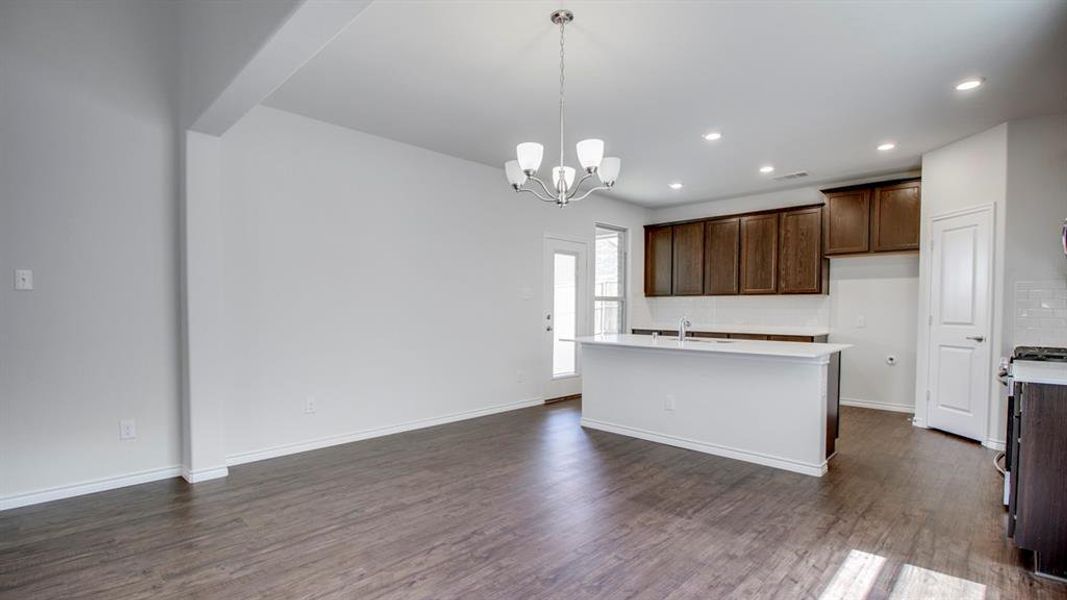 Kitchen with decorative light fixtures, dark brown cabinets, a chandelier, dark wood-style floors, and recessed lighting Kitchen with decorative light fixtures, dark brown cabinets, a chandelier, dark wood-style floors, and recessed lighting