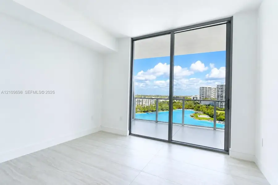 Interior space featuring floor-to-ceiling sliding glass doors, neutral tile flooring, and a covered balcony with a glass railing