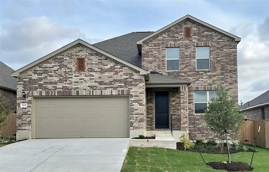 View of front of property featuring concrete driveway, brick siding, a shingled roof, and a garage
