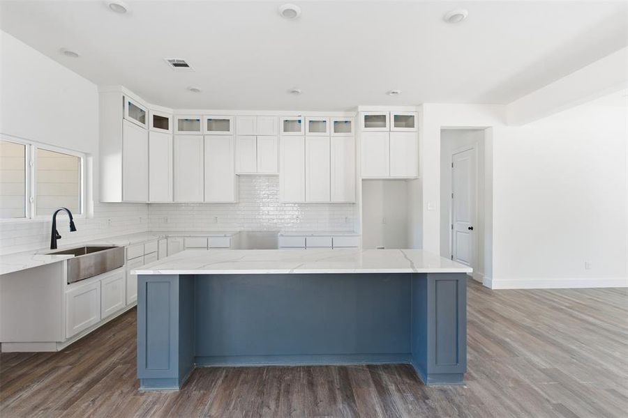Kitchen featuring white cabinetry, tasteful backsplash, dark wood-style floors, light stone countertops, and recessed lighting Kitchen featuring white cabinetry, tasteful backsplash, dark wood-style floors, light stone countertops, and recessed lighting