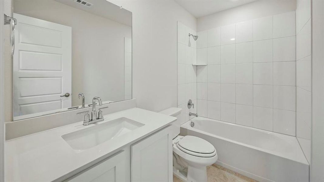 Bathroom featuring a white vanity with an integrated sink, polished chrome faucet, and a large wall-mounted mirror Bathroom featuring a white vanity with an integrated sink, polished chrome faucet, and a large wall-mounted mirror