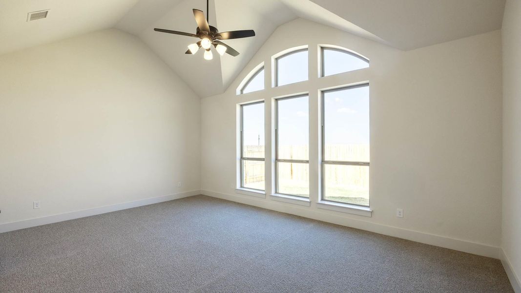 Carpeted empty room with a ceiling fan and high vaulted ceiling