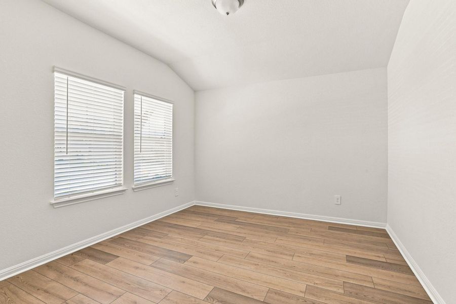 A vaulted ceiling and wood-look flooring enhance this light-filled, versatile room.