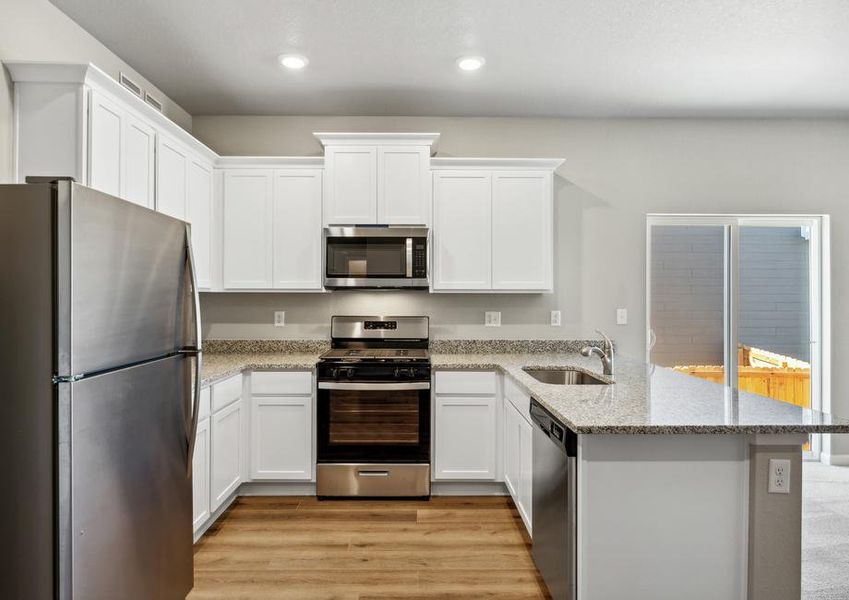 The kitchen has stainless steel appliances and plank flooring.