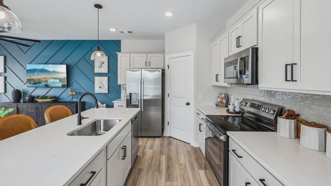 View of kitchen with quartz countertops, tile backsplash, and pendant lighting