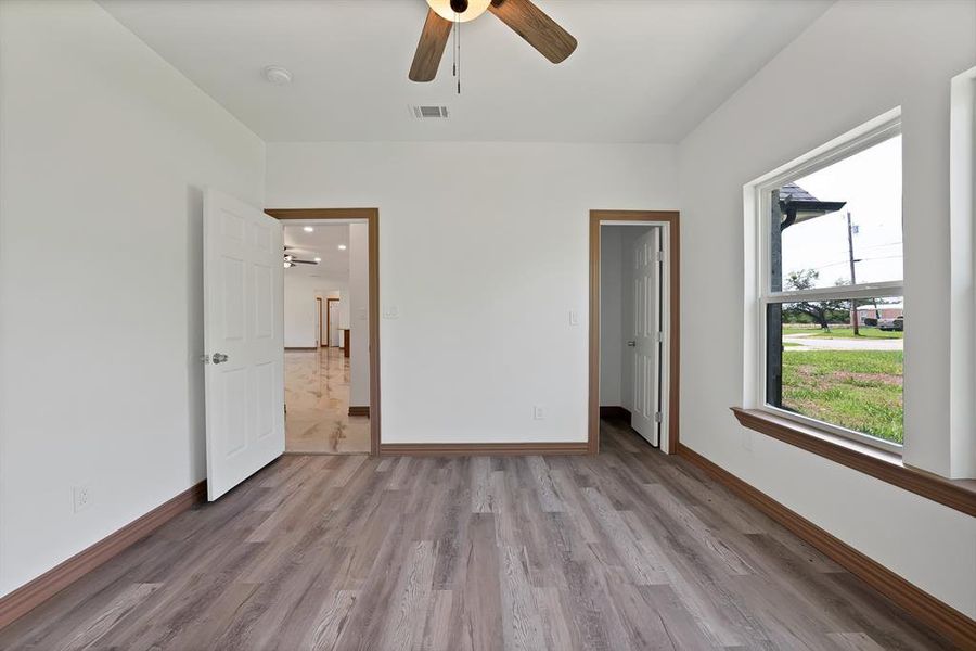 Unfurnished bedroom with light wood-style flooring, a ceiling fan, and a spacious closet