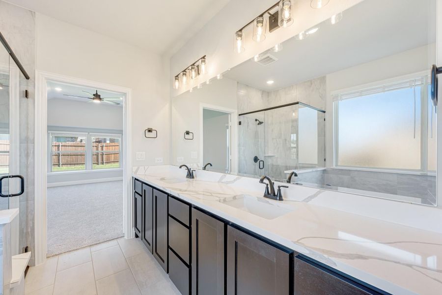 Master bathroom with double vanity, dark cabinets, quartz countertops, and glass shower enclosure Master bathroom with double vanity, dark cabinets, quartz countertops, and glass shower enclosure