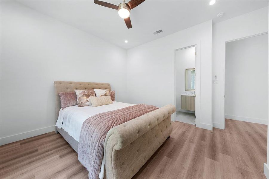 Bedroom with light wood-style flooring, recessed lighting, a ceiling fan, and connected bathroom Bedroom with light wood-style flooring, recessed lighting, a ceiling fan, and connected bathroom