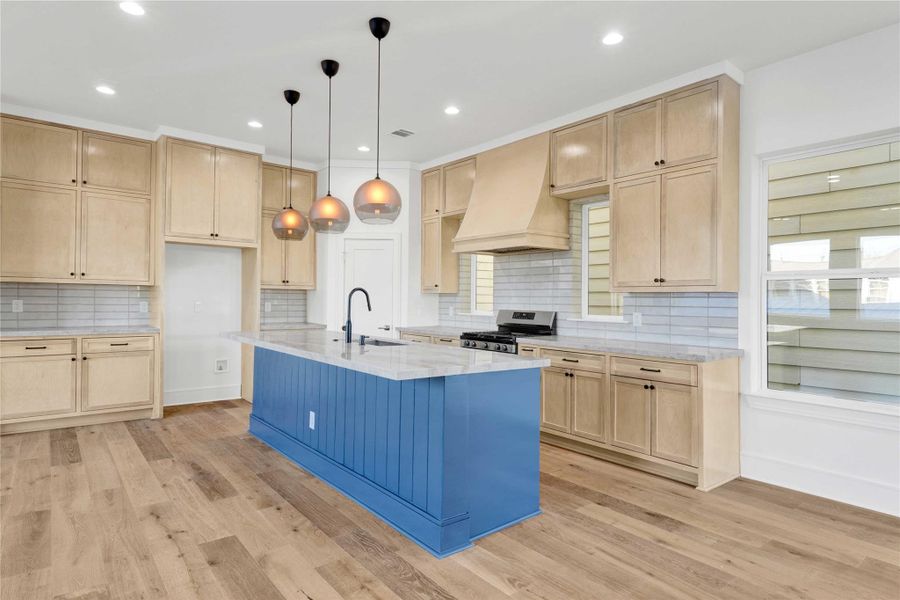 Second-floor main living and kitchen area with abundant natural light, high ceilings, engineered wood floors, custom built-ins, and a stunning custom fireplace as the focal point. Features an oversized island with Taj Mahal quartzite countertops and integrated appliances.