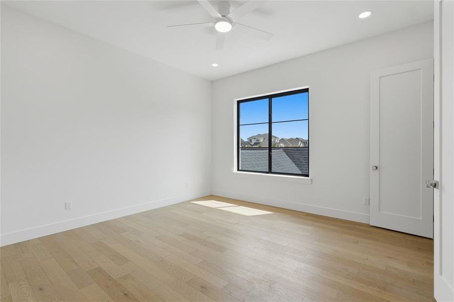 Spacious room featuring light wood-finish flooring and crisp white walls