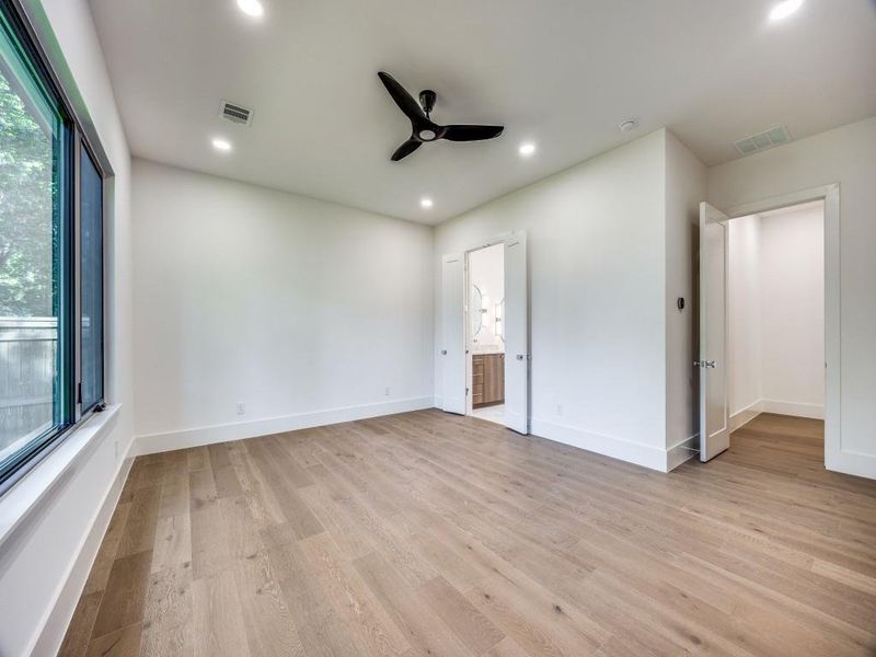 Unfurnished bedroom featuring light wood-type flooring, ensuite bath, and ceiling fan