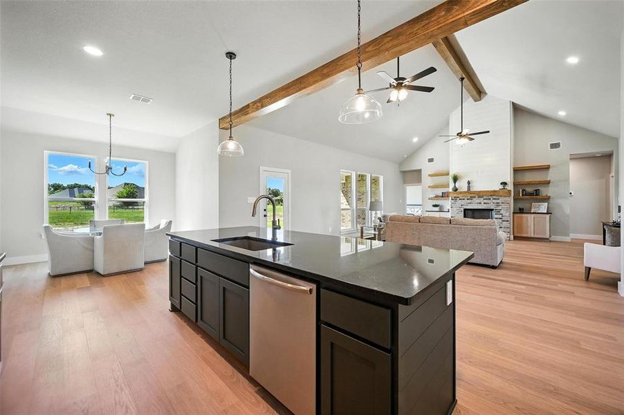 Kitchen featuring a high ceiling, dishwasher, pendant lighting, light wood-type flooring, and open floor plan
