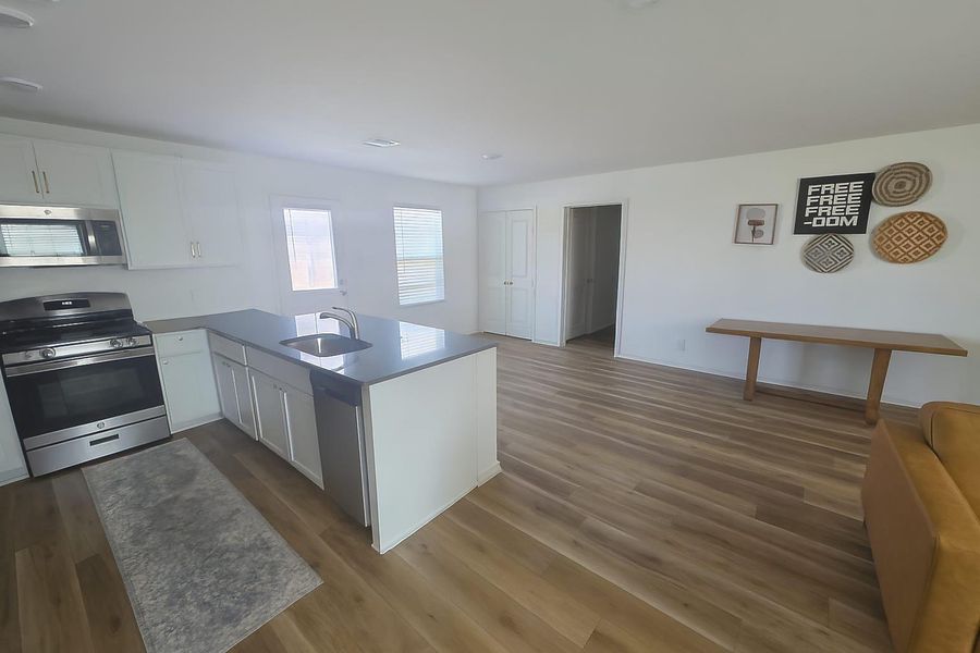 Kitchen with a peninsula, stainless steel appliances, white cabinets, dark wood-style flooring, and open floor plan Kitchen with a peninsula, stainless steel appliances, white cabinets, dark wood-style flooring, and open floor plan