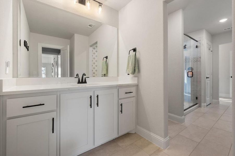 Bathroom with vanity, light tile patterned floors, and a stall shower