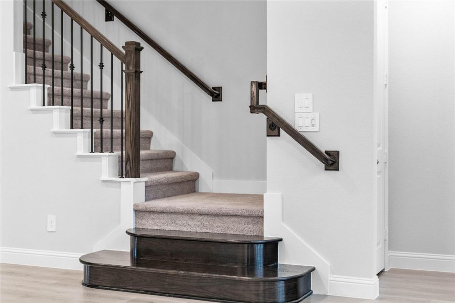 This elegant staircase serves as a sophisticated focal point, featuring a striking contrast between its richly stained wood handrails and the crisp white trim and risers.