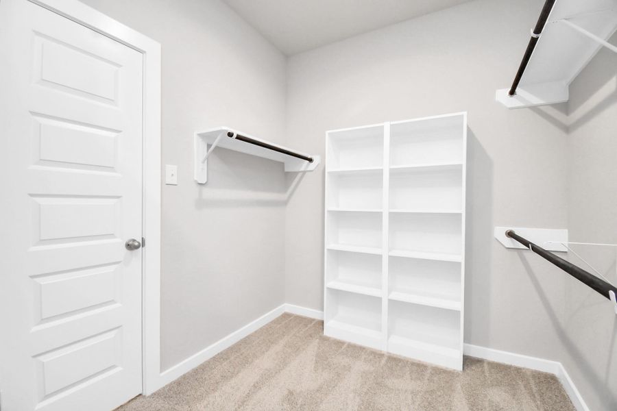 Discover luxury in this expansive walk-in closet, adorned with high ceilings and luxurious carpet. Sample photo of completed home with similar floor plan. Actual colors and selections may vary.