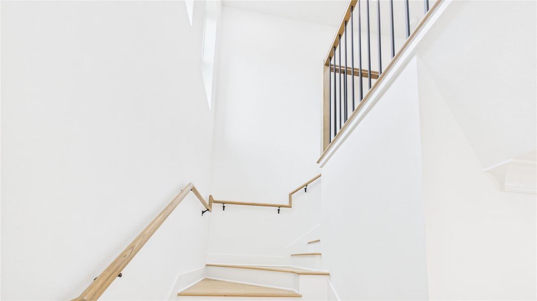 Bright, modern staircase with light wood steps and sleek metal railing, offering a clean and airy feel.