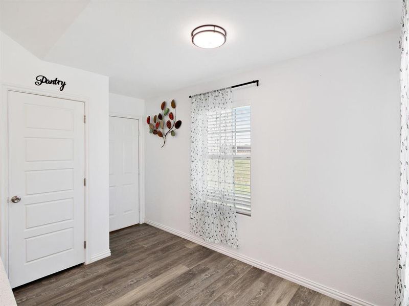 Interior space featuring wood-finish flooring, white baseboards, and a window with horizontal blinds