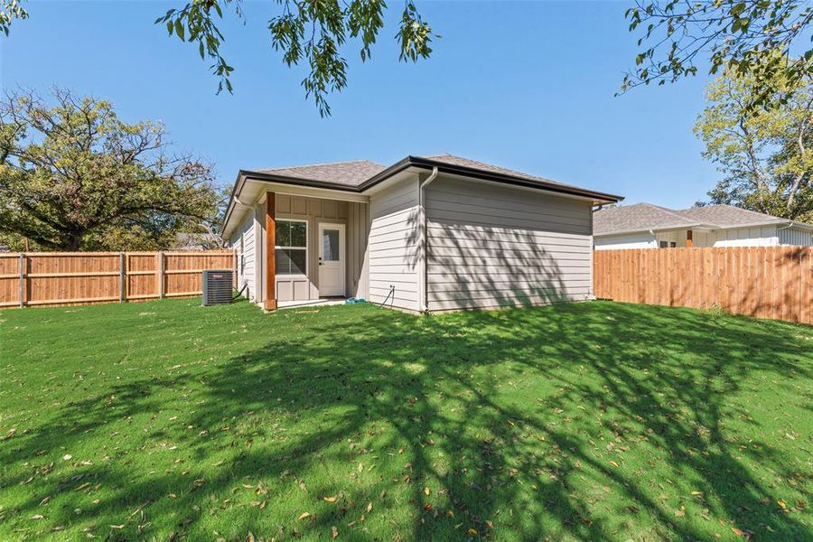 Back of house featuring a fenced backyard and a shingled roof Back of house featuring a fenced backyard and a shingled roof
