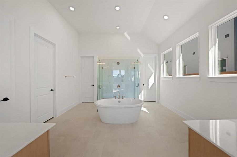 Full bathroom with a freestanding bath, a stall shower, vaulted ceiling, vanity, and recessed lighting Full bathroom with a freestanding bath, a stall shower, vaulted ceiling, vanity, and recessed lighting