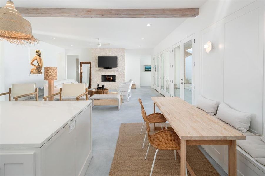 Dining room featuring a stone fireplace, french doors, beamed ceiling, and ceiling fan Dining room featuring a stone fireplace, french doors, beamed ceiling, and ceiling fan