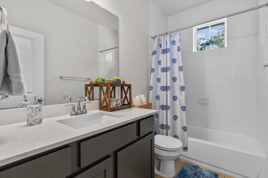 White tiled tub surround pairs with solid countertops and dark-finished cabinetry.