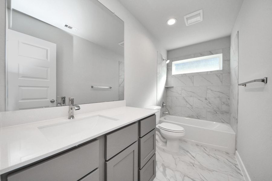 Secondary bath features tile flooring, bath/shower combo with tile surround, light stained wood cabinets, beautiful light countertop. Secondary bath features tile flooring, bath/shower combo with tile surround, light stained wood cabinets, beautiful light countertop.
