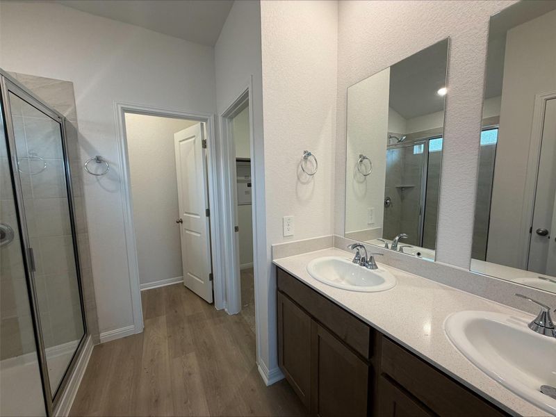 Full bath with a stall shower, dark wood-type flooring, double vanity, and a walk in closet