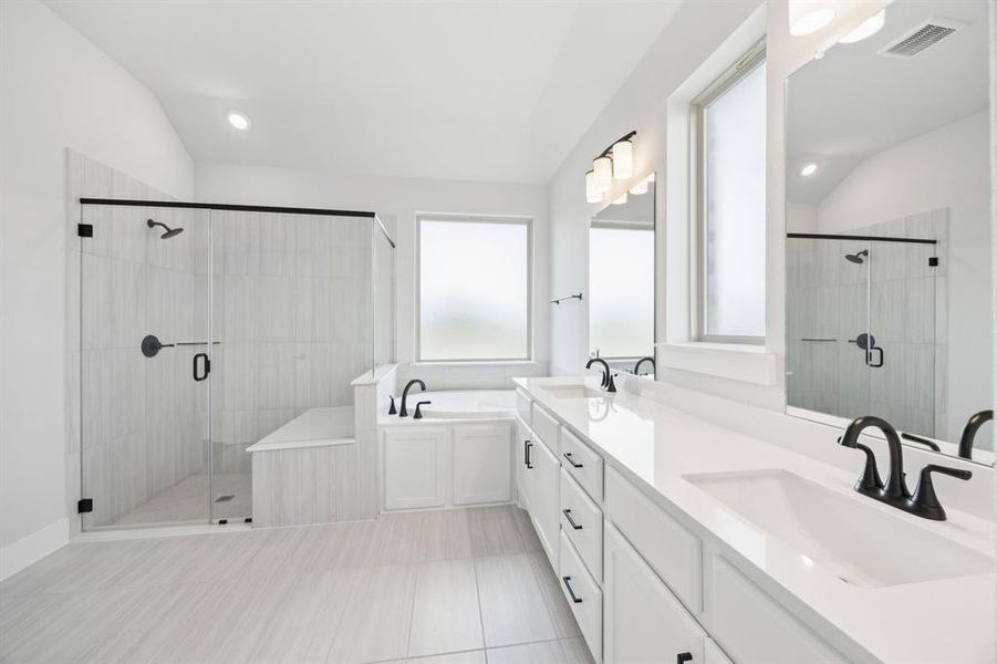 Bathroom with lofted ceiling, a stall shower, a garden tub, double vanity, and light tile patterned floors