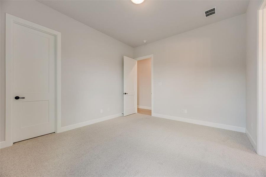 Unfurnished bedroom with light colored carpet and baseboards