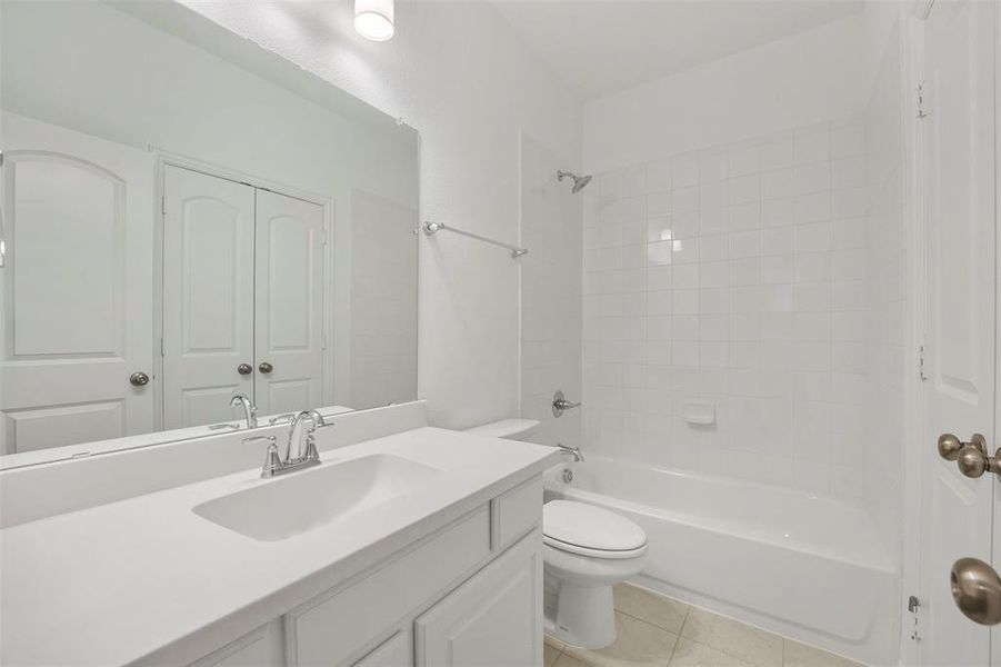 Full bathroom featuring tile patterned flooring, tiled shower / bath combo, vanity, and toilet