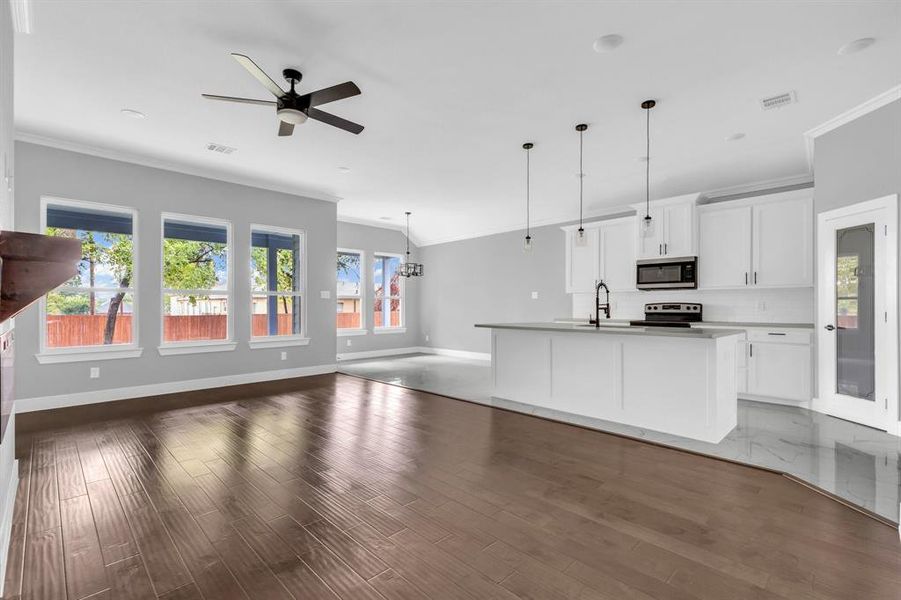 Kitchen with dark wood-type flooring, a center island with sink, white cabinets, and appliances with stainless steel finishes