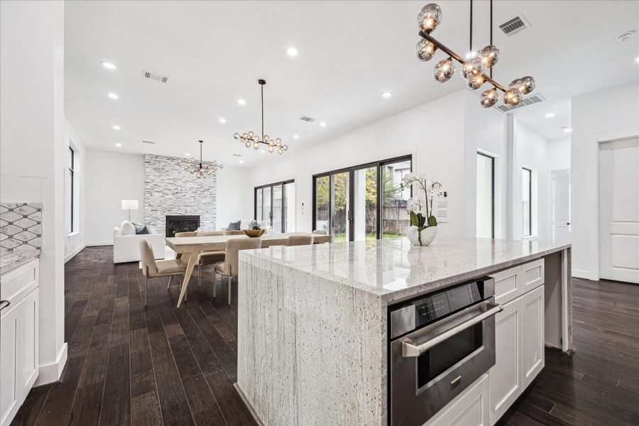 The open-concept living, dining, and kitchen are bathed in natural light, with walls of windows and sliding glass doors that connect the interior to the backyard.