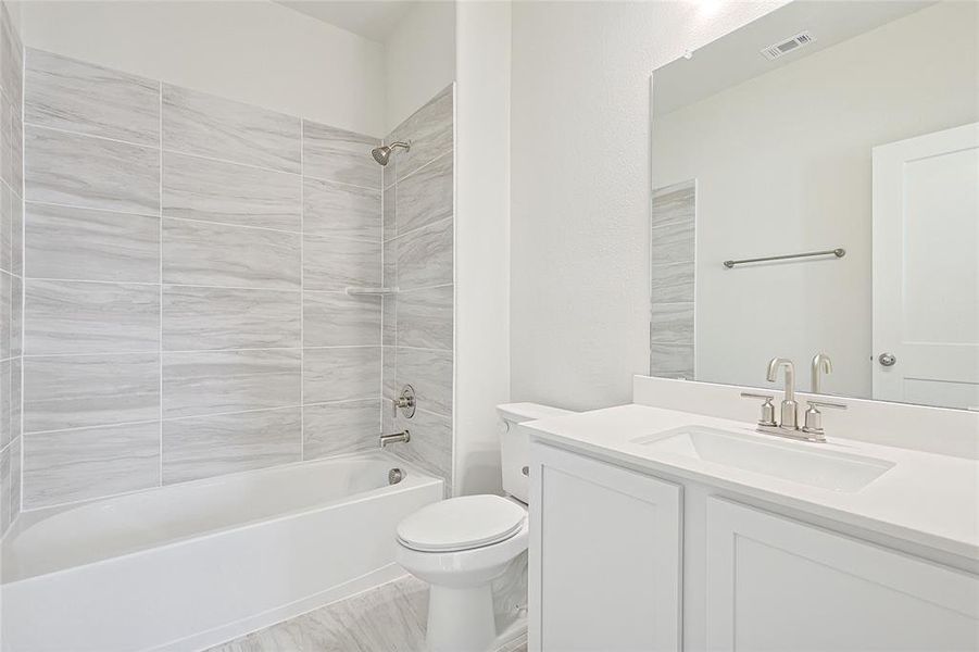 The bathroom features a vanity with a white countertop and an undermount sink, a toilet, and a bathtub with tile surround