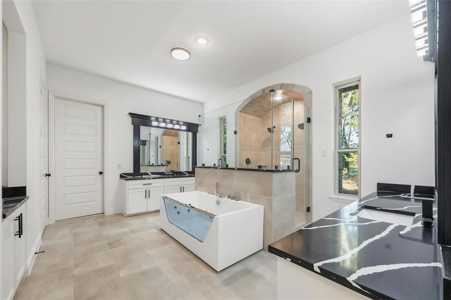 Bathroom featuring two vanities, a shower stall, and a freestanding tub