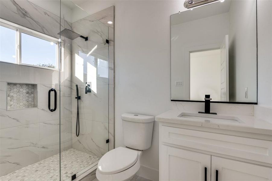 Bathroom with vanity and a marble finish shower