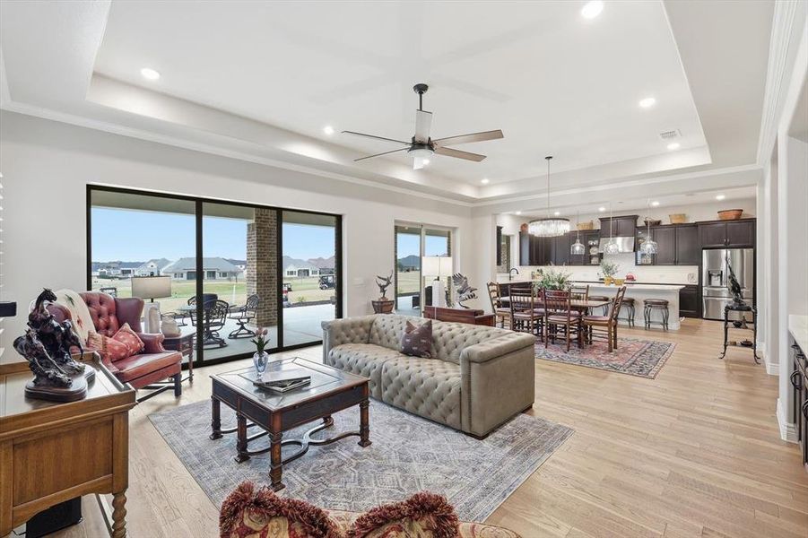 Grand Great Room anchored by an Impressive Built-in Bar designed for Effortless Entertaining. A Wall of Three-Panel Sliding Glass Doors opens to the Covered Outdoor Living Pavilion showcasing Panoramic Golf Course and Territorial Views.
