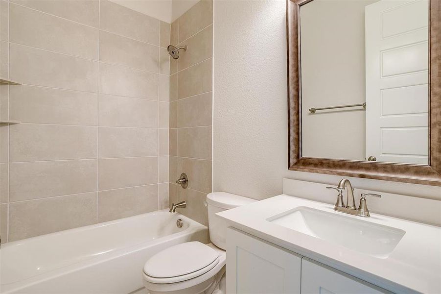 Full bathroom featuring toilet, tiled shower / bath, and vanity