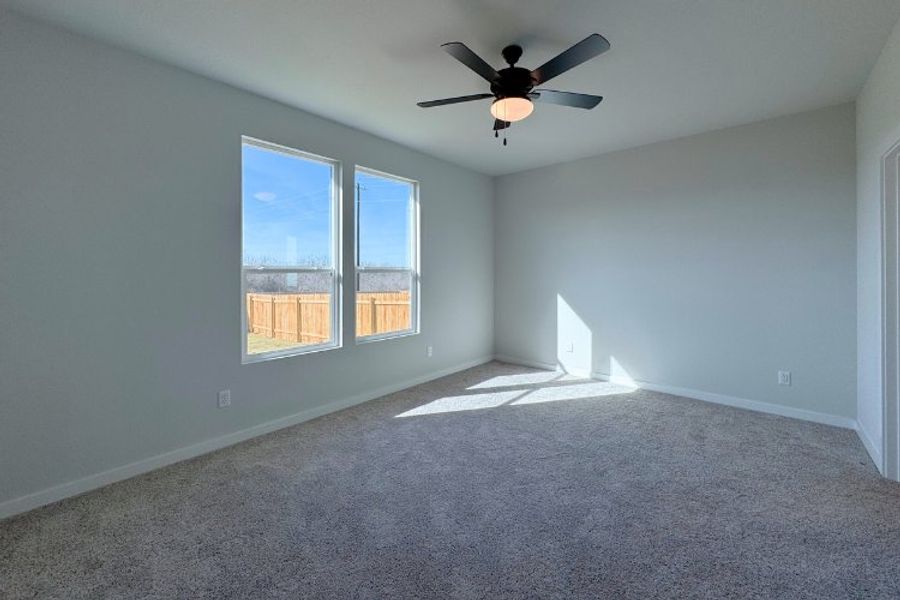 A room with a ceiling fan and a window with a view of the city.