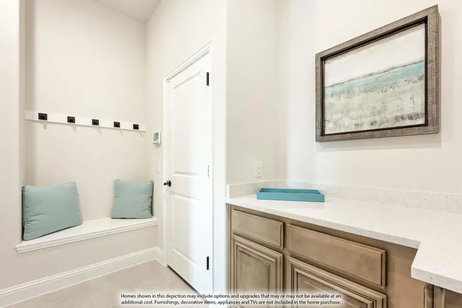 Mudroom with built-in bench, wall hooks, and wood cabinets with white countertop Mudroom with built-in bench, wall hooks, and wood cabinets with white countertop