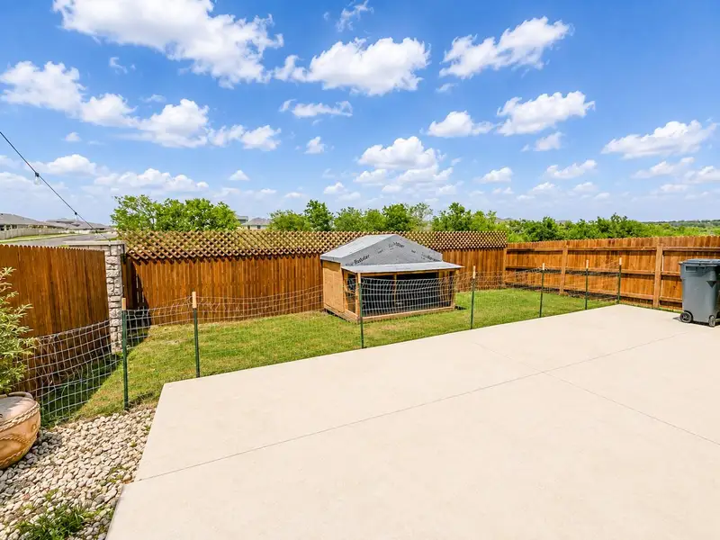 A spacious backyard features a concrete patio, grassy lawn, and privacy fencing. A spacious backyard features a concrete patio, grassy lawn, and privacy fencing.