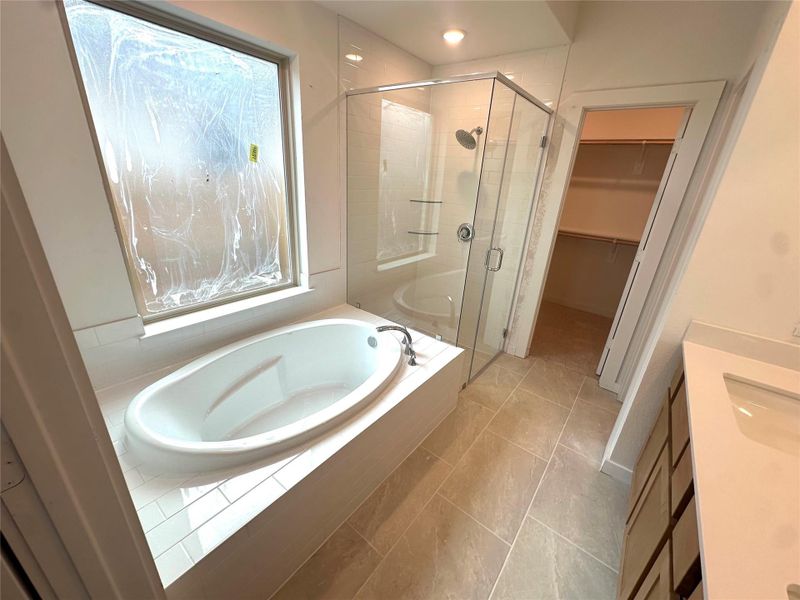 Large soaker tub with separate glass shower showcasing tile to ceiling and tiled shower floor.